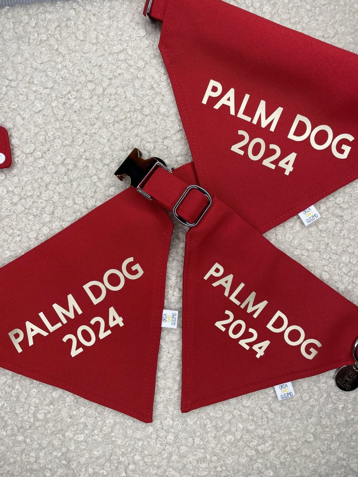 Bandanas rouges floqués « Palm Dog 2024 » en lettres dorées, avec l’étiquette Oria & Guizmo cousue sur le bord